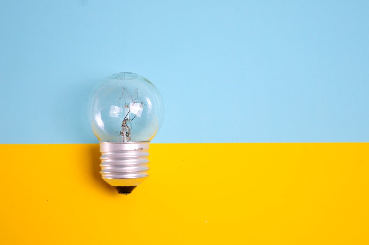 Accueil A clear light bulb against a vibrant blue and yellow background, symbolizing energy and creativity.